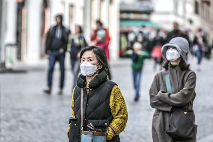 Dopo virus: Due giovani donne asiatiche con la mascherina, per le strade di Roma