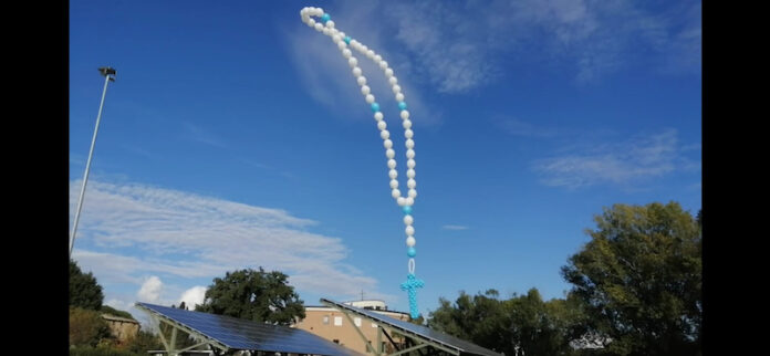 Un rosario fatto di palloncini bianchi e celesti in cielo