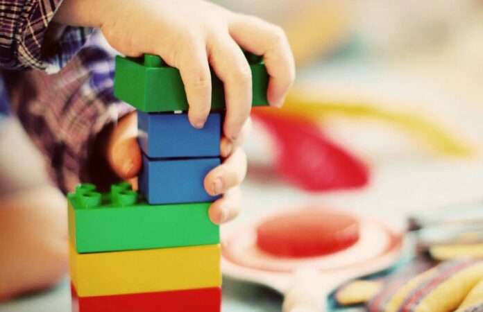 Mani di un bambino giocanocon le costruzioni