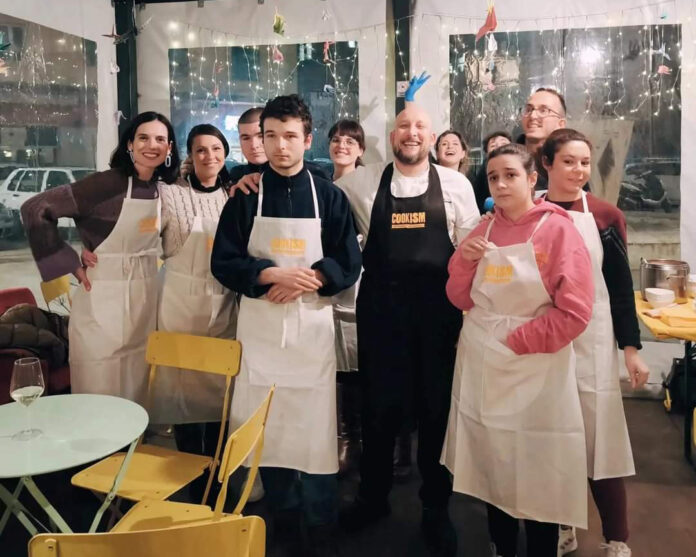 Foto di gruppo dei ragazzi con autismo con i grembiuli bianchi, al centro lo chef Daniele Guerra