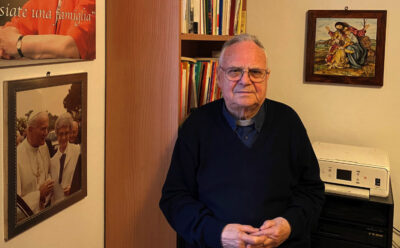 Mons. Giuseppe Ricci nel suo studio nella canonica a Ponte Felcino. Accanto, appesa al muro la foto di Chiara Lubich con il Papa.