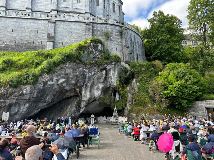 La celebrazione nella grotta di Massabielle a Lourdes, davanti i pellegrini seduti