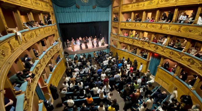 Tanti giovani seduti sulle poltronicine del Teatro e sui palchetti, sul palco i frati minori