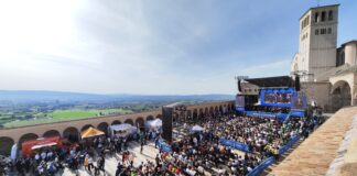 La piazza Inferiore della Basilica di Assisi con le persone sedute sulle sedie davanti al palco, veduta dall'alto