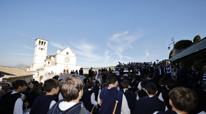 pellegrini di spalle sullo sfondo la basilica superiore di San Francesco ad Assisi