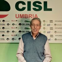 Luigi Fabiani a mezzo busto sullo sfondo il manifesto della Cisl Umbria