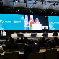 La sala con i presenti alla Cop 29 sullo sfondo una grande schermo con la presidente Meloni che parla