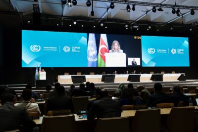 La sala con i presenti alla Cop 29 sullo sfondo una grande schermo con la presidente Meloni che parla