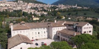 Veduta dall'alto del Seminario regionale umbro immerso nella vegetazione, sullo sfondo Assisi