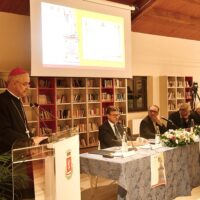 I relatori interventi all'Atto accademico per il 60° della proclamazione di san Benedetto patrono d'Europa seduti al tavolo, sullo sfondo una libreria e un schermo illuminato