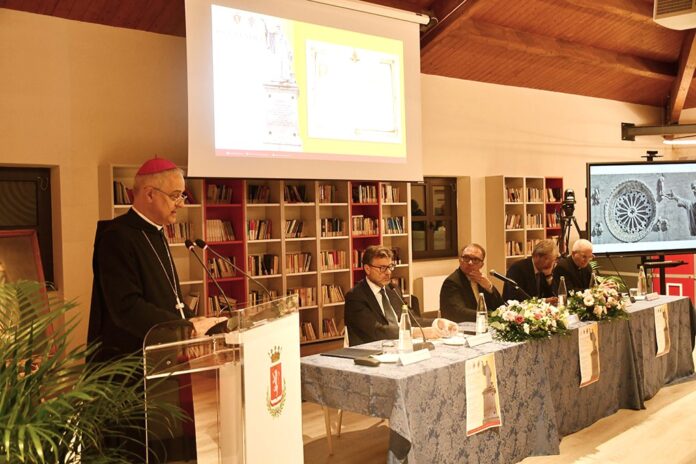 I relatori interventi all'Atto accademico per il 60° della proclamazione di san Benedetto patrono d'Europa seduti al tavolo, sullo sfondo una libreria e un schermo illuminato