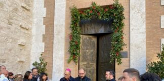 Davanti alla porta della cattedrale al centro l'arcivescovo Ivan Maffeis e il vicario generale don Simone Sorbaioli mentre leggo la Bolla di indizione del Giubileo