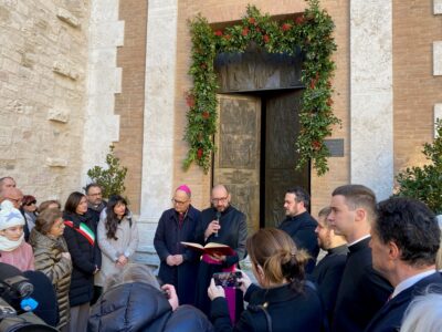 Davanti alla porta della cattedrale al centro l'arcivescovo Ivan Maffeis e il vicario generale don Simone Sorbaioli mentre leggo la Bolla di indizione del Giubileo