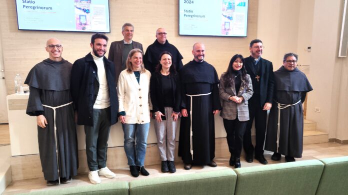 Foto di gruppo in piedi di alcuni partecipanti alla presentazione dei dati sui pellegrini, tra loro il custode del sSacro Convento fra Marco Moroni, la presidente della regione Stefania Proietti, il vescovo di Gubbio Luciano Paolucci Bedini e alcuni frati francescani